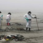 Personal de limpieza limpia y recoge basura, hoy en la playa Cavero en el distrito de Ventanilla en Lima (Perú).