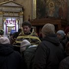 Uno de los sacerdotes de la Catedral Svyato-Uspensky, de la Iglesia Ortodoxa Ucraniana, ofrece una cruz a los fieles para que la besen durante el oficio. EFE/Manuel Bruque
