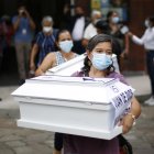 Una mujer lleva el ataúd que contiene las osamentas de un familiar, asesinado 1980 por el ejército salvadoreño, hoy, en San Salvador (El Salvador).
