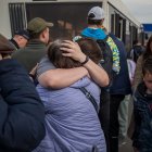 Refugiados se abrazan hoy martes 3 de mayo de 2022 tras llegar al estacionamiento de un centro comercial en Zaporiyia (Ucrania). La viceprimera ministra de Ucrania, Iryna Vereshchuk, anunció este martes el éxito de la "primera parte" de la operación para rescatar de la acería de Azovstal a un convoy con cerca de 150 mujeres, ancianos y niños que, según dijo, llegarán pronto a Zaporiyia. EFE/ MIGUEL GUTIÈRREZ