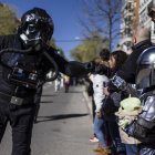 Un piloto del cuerpo imperial de cazas estelares TIE de la saga Star Wars (i) saluda a un pequeño mandaloriano (d) durante el desfile del Galaxy Day por una calle de Madrid.