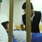Atención. Un niño se recupera de un tratamiento hospitalario, mientras recibe la visita de un conocido.
