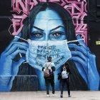 Un mural en Bogotá, donde una mujer sostiene una mascarilla, hace referencia a la terrible pandemia de la COVID-19 en el mundo.