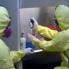 Imagen de archivo de dos médicos con trajes protectores.