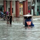 Varias personas caminan por una calle llena de agua, hoy en La Habana (Cuba).