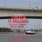 Fotografía cedida por Amazon Watch donde se aprecia a un hombre mientras observa una pancarta gigante