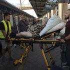 Voluntarios suben a una anciana a un vagón, donde van las personas que huyen de las zonas de combates en un tren de la "Ukrzaliznytsia", la empresa estatal de ferrocarriles, ayer en Dnipro (Ucrania). EFE/Orlando Barría