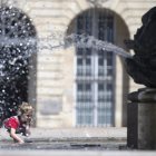 Un niño se rocía con agua de la fuente en la Place de la Bourse, durante la ola de calor, en la ciudad francesa de Burdeos.