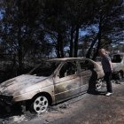 Una mujer observa los coches quemados del incendio acaecido en Anthousa, cerca de Atenas, Grecia.