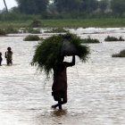 Varias personan vadean un área inundada tras las fuertes lluvias en Sanghar, Pakistán, el 23 de agosto de 2022.
