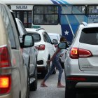 Una  niña esquiva los autos del tráfico mientras intenta comercializar fundas de basura