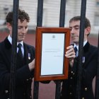 Miembros de la casa real británica publican el anuncio oficial de la muerte de la reina Isabel II en las puertas del Palacio de Buckingham este jueves.