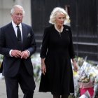 El rey Carlos III (izq) y Camila, la reina consorte, miran los tributos florales dejados fuera del Palacio de Buckingham este 9 de septiembre.