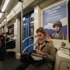 Una mujer viaja en el metro sentada frente a un cartel en el que se muestra a un soldado ruso, este martes en Moscú (Rusia).