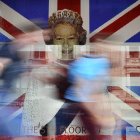 Unos niños corren frente a una imagen de la difunta reina Isabel II frente a la bandera de la Unión hecha completamente de lego en una tienda de juguetes en Londres.