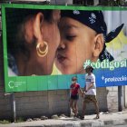 Un hombre y su hija pasan caminando frente a una valla que hace parte de la campaña por el SÍ en el referendo sobre el código de familia, hoy en La Habana (CUBA).