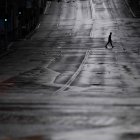 Fotografía de archivo de un transeúnte que cruza una calle completamente vacía en Sídney, Australia.