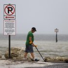 Un hombre camina con un detector de metales por lo que los lugareños reportaron como una costa expuesta por aguas mucho más retrocedidas de lo normal ante la llegada del huracán Ian, en Clearwater, Florida.