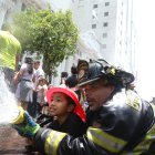 Los bomberos enseñaron a los niños a manejar una manguera para apagar un incendio.