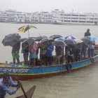 Los pasajeros de Bangladesh cruzan el río Buriganga mientras sostienen paraguas durante una fuerte lluvia y las duras condiciones causadas por el ciclón Sitrang EFE/EPA/MONIRUL ALAM