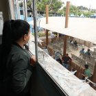 Destrucción. Entre los ventanales rotos de su departamento, Gabriela Pino observa los trabajos de reconstrucción en los bajos del edificio que fue afectado por la explosión de una bomba, afuera del Municipio de Durán.