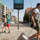 Sevilla. Varias personas pasan ante el termómetro próximo a la estación de autobuses de Plaza de Armas de esta ciudad española en un día en que las temperaturas máximas superan los 40 grados.