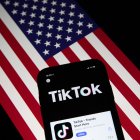 Fotografía de archivo que muestra la aplicación TikTok en la pantalla de un teléfono celular, con la bandera estadounidense de fondo.