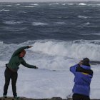 Los turistas observan el fuerte oleaje esta tarde en la costa de Muxía, en la Costa de la Muerte. Tras el paso ayer lunes de la borrasca Gérard, la parte más adversa de este temporal invernal corresponderá a la borrasca Fien, que a partir de este martes mantiene activado el aviso rojo en Galicia por olas de 9 metros y en otras 12 comunidades en naranja por nieve en cotas bajas, lluvias y fuerte viento. EFE/Lavandeira jr