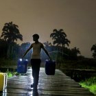 Los comuneros a oscuras van en busca de sus baldes llenos de agua por la lluvia
