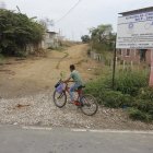 Obras. Las localidades al pie de un letrero que anuncia obras en la parroquia siguen en pura tierra.