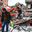 Personas transportan alimentos rescatados de un edificio derrumbado tras un fuerte terremoto en el distrito de Elbistan de Kahramanmaras, sureste de Turquía, el 07 de febrero de 2023