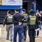 Varios  agentes mientras acompañan a una de las personas arrestadas durante un operativo