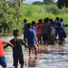 Unos niños caminan en medio de una inundación en la comunidad Rancho Chico perteneciente al municipio de Okinawa