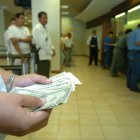 Dinero.- Una persona cuenta los dólares que ha recibido en un banco.