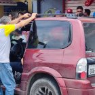 Allegados y curiosos observan el cadáver de un hombre baleado dentro de su vehículo.
