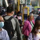 Viajeros, algunos de ellos todavía con mascarillas, esperan en una parada de autobús en Hong Kong, China, 01 de marzo de 2023
