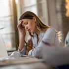 Young displeased businesswoman having a headache while working in the office.