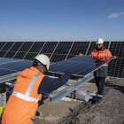 Dos técnicos reemplazan un panel fotovoltaico después de que fuera dañado por una piedra que rebotó en un automóvil que pasaba.