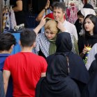 Una mujer se ajusta el velo, mientras camina por una calle