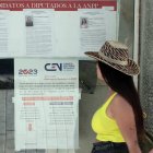 Dos mujeres pasan frente a unos carteles informativos sobre el proceso electoral del domingo.