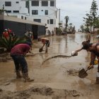 un grupo de personas al remover el lodo de una calle anegada por las lluvias, en el balneario de Punta Hermosa, al sur de Lima (Perú).