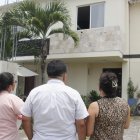 Vecinos observan, consternados, la casa donde el lunes 20 de marzo tres miembros de una familia murieron intoxicados.