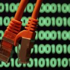 Imagen de archivo de unos cables sobre una pantalla de ordenador con un código binario en Colonia, Alemania. EFE/Oliver Berg