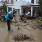 Personas ayudan a remover el lodo en una calle afectada por las lluvias, en el balneario de Punta Hermosa al sur de Lima (Perú), en una fotografía de archivo.