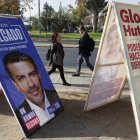 Personas caminan frente a carteles de propaganda electoral para consejeros Constitucionales, el 27 de abril 2023, en Santiago (Chile). Chile celebra este domingo sus segundas elecciones constituyentes en dos años, pero el contexto actual dista mucho de la efervescencia de 2021, cuando aún estaba presente el estallido de 2019, y la hoja de ruta acordada ahora para escribir la nueva Constitución es muy diferente. EFE/Elvis González