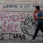 Un hombre camina frente a un mural pidiendo "Refundar Chile"