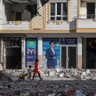 Tránsito. Una mujer con su hija caminan entre las ruinas que ha dejado el sismo y que aún no han podido desalojarse en la ciudad de Nurdagi.