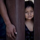 Janina (derecha), niña ecuatoriana de 4 años, mira a través del muro fronterizo mientras espera con su padre Jaime (izquierda) que los agentes de la Patrulla Fronteriza la lleven a un centro de procesamiento a lo largo de la frontera entre México y Estados Unidos.