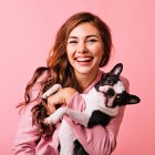 Wonderful european female model chilling in studio with puppy. Indoor portrait of debonair girl enjoying photoshoot with her cute pet.