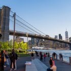 Varias personas transitan por el parque de Dumbo, ubicado a un costado del puente de Brooklyn.